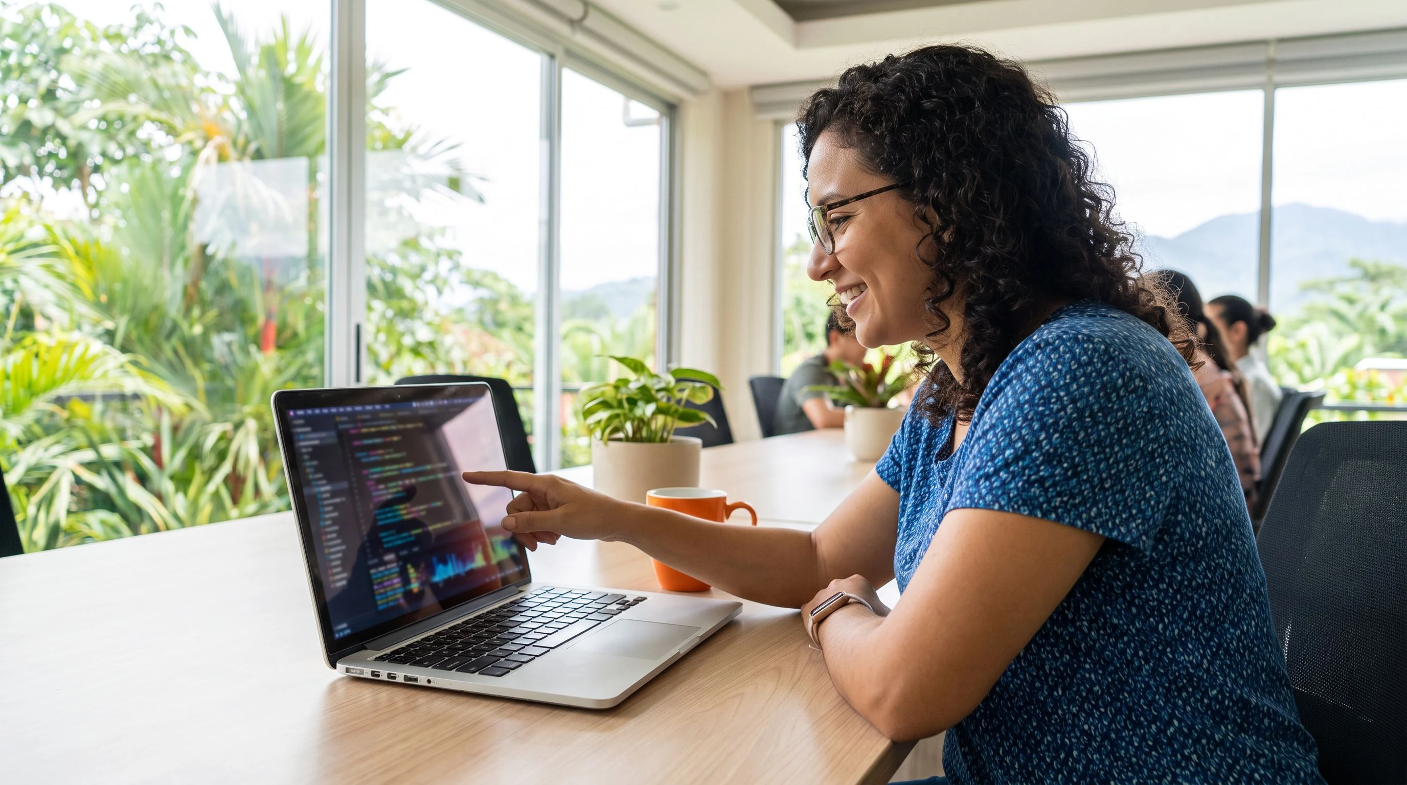 Engineering manager reviewing nearshore AI engineer candidates on a laptop in a modern office with orange accents