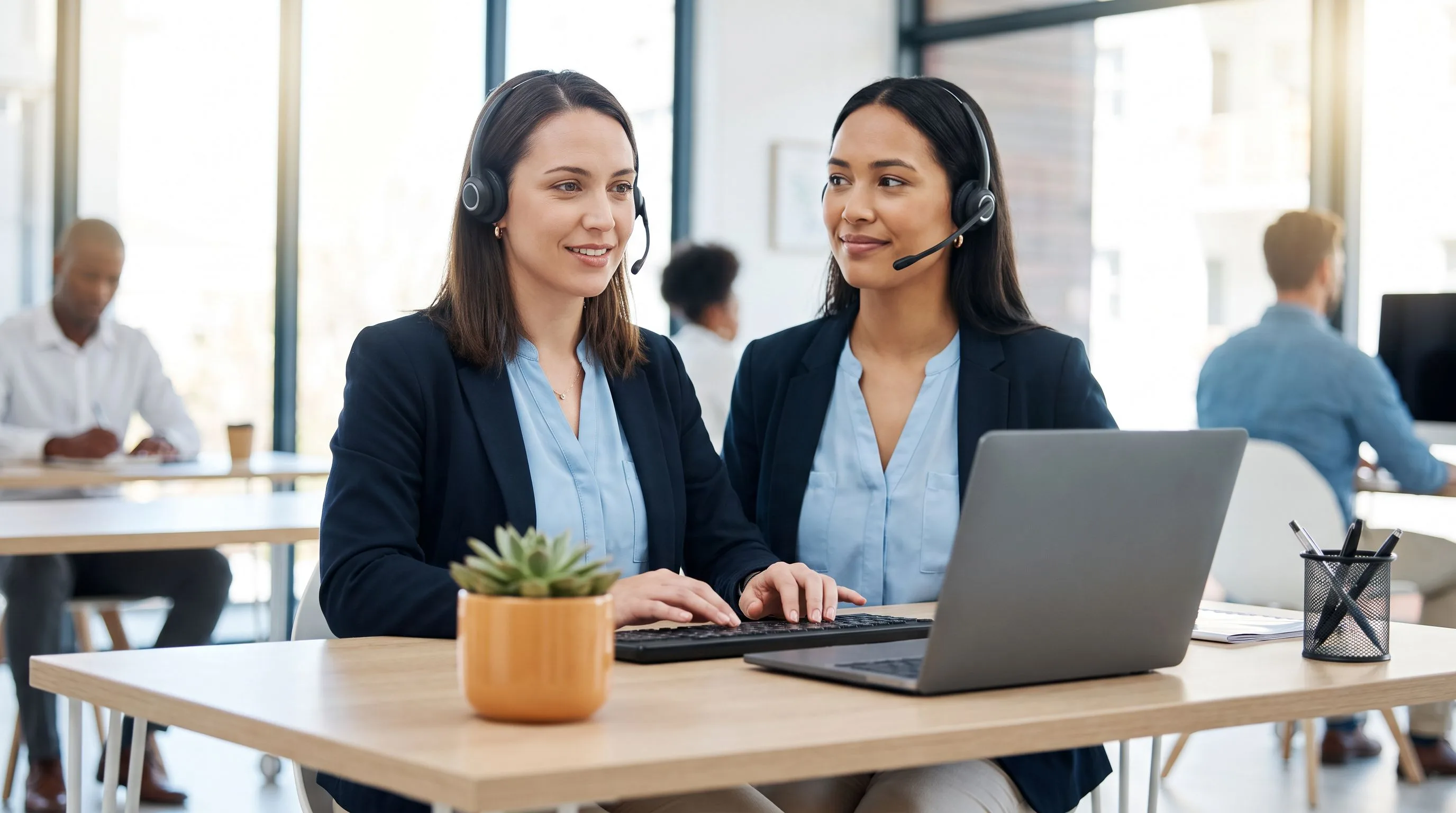 CSR candidate wearing a headset completing a mock call assessment at a clean offshore support desk with orange plant accent