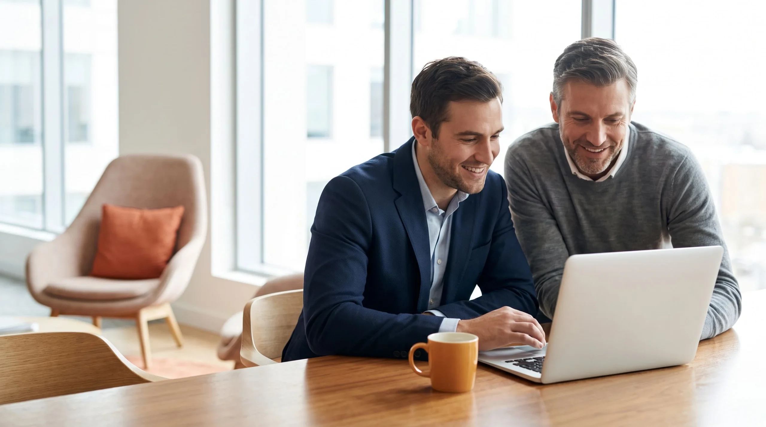 Hiring manager and colleague reviewing an IT support specialist candidate profile together on a laptop in a modern office