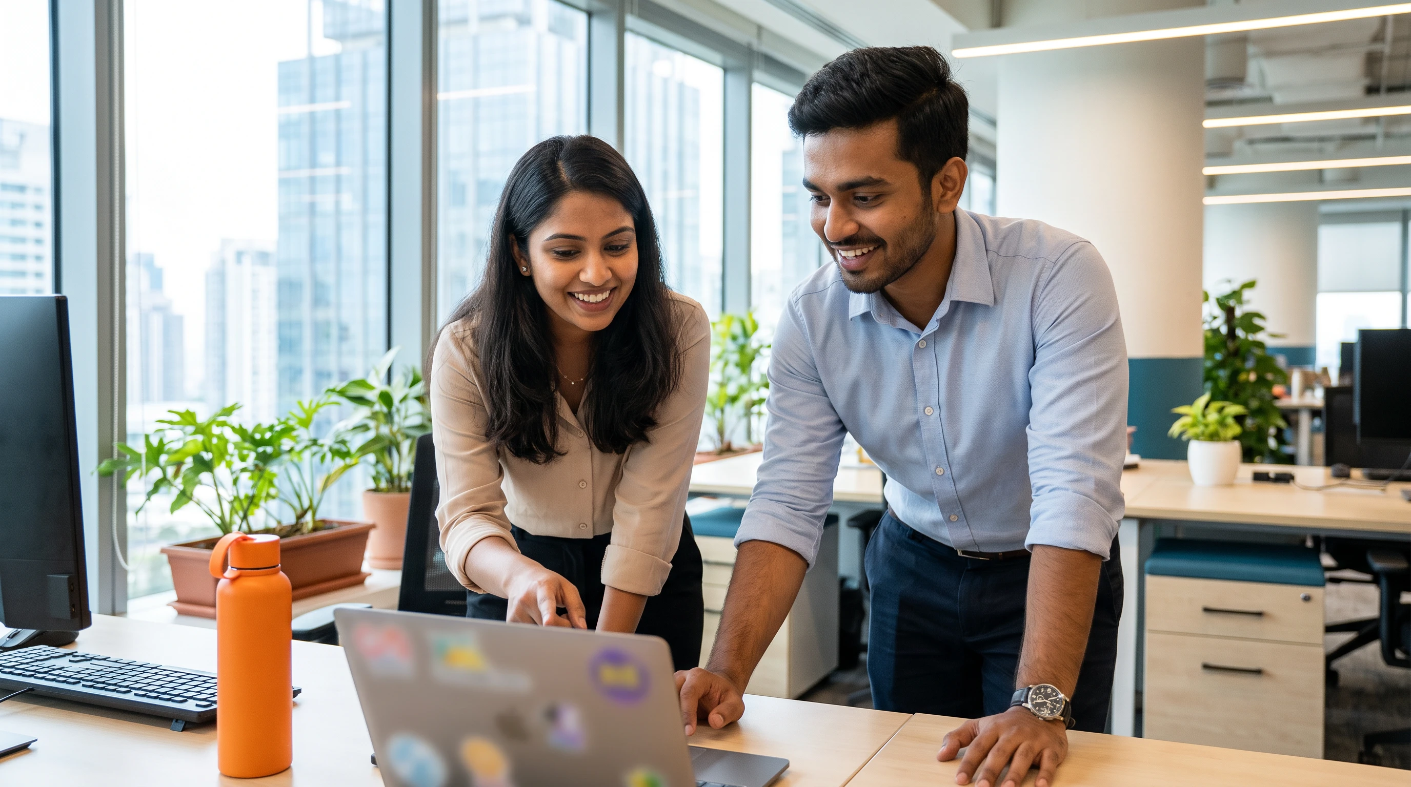 Offshore IT support team members reviewing a support ticket dashboard together on a laptop