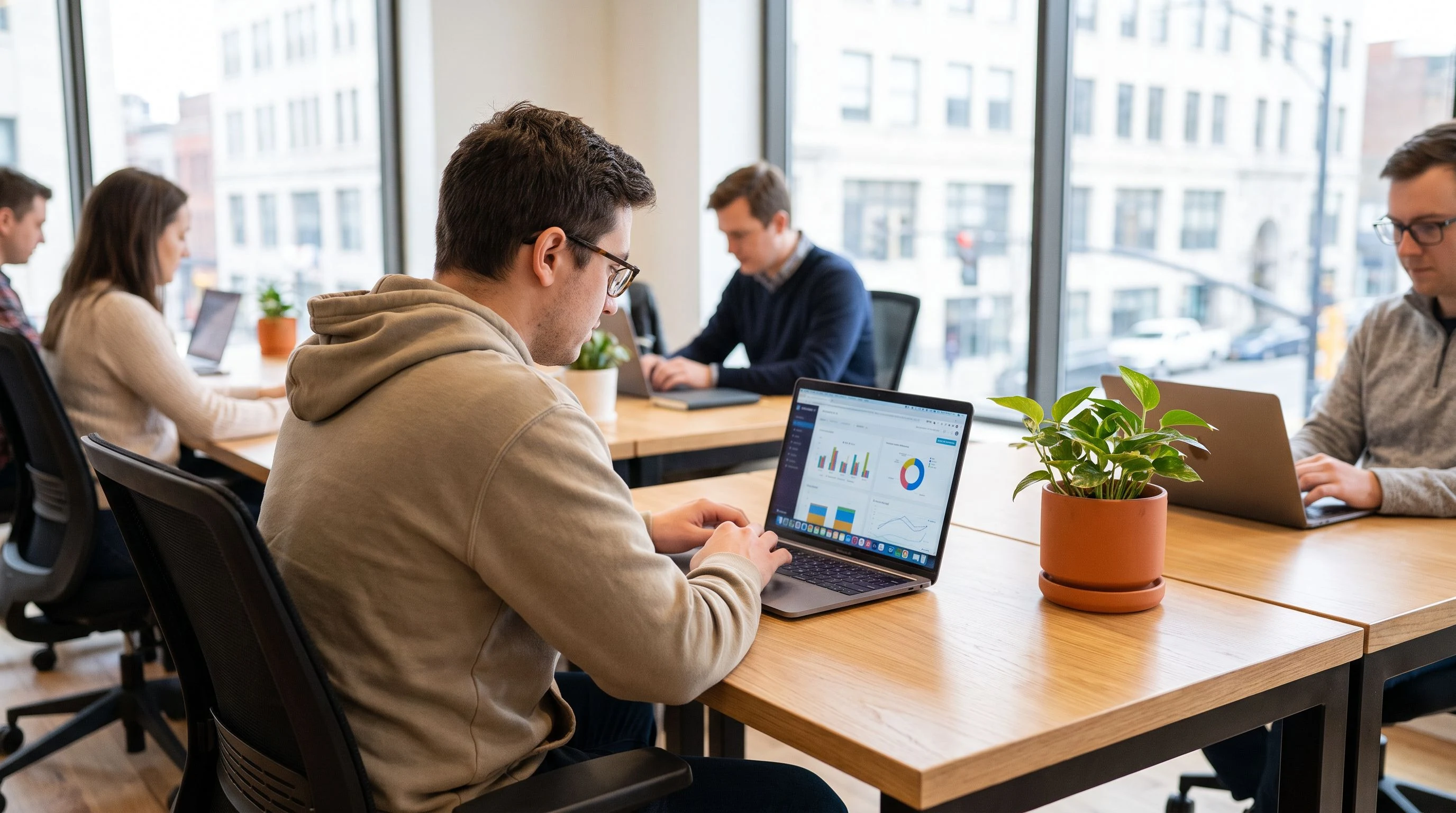 Engineer reviewing model fine-tuning metrics on a laptop screen, collaborative workspace