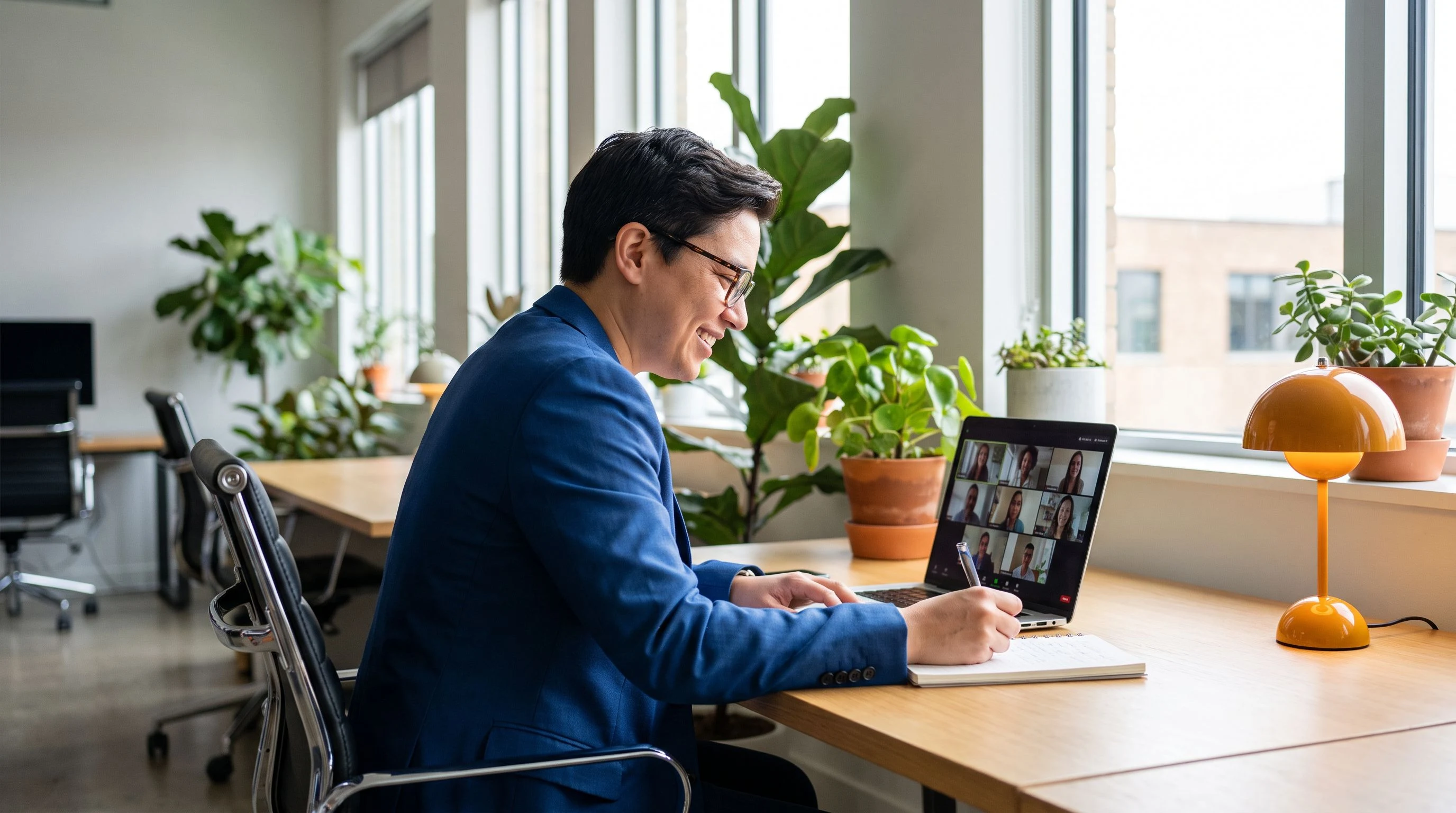 Recruiter on a video call taking notes on a laptop in a bright office