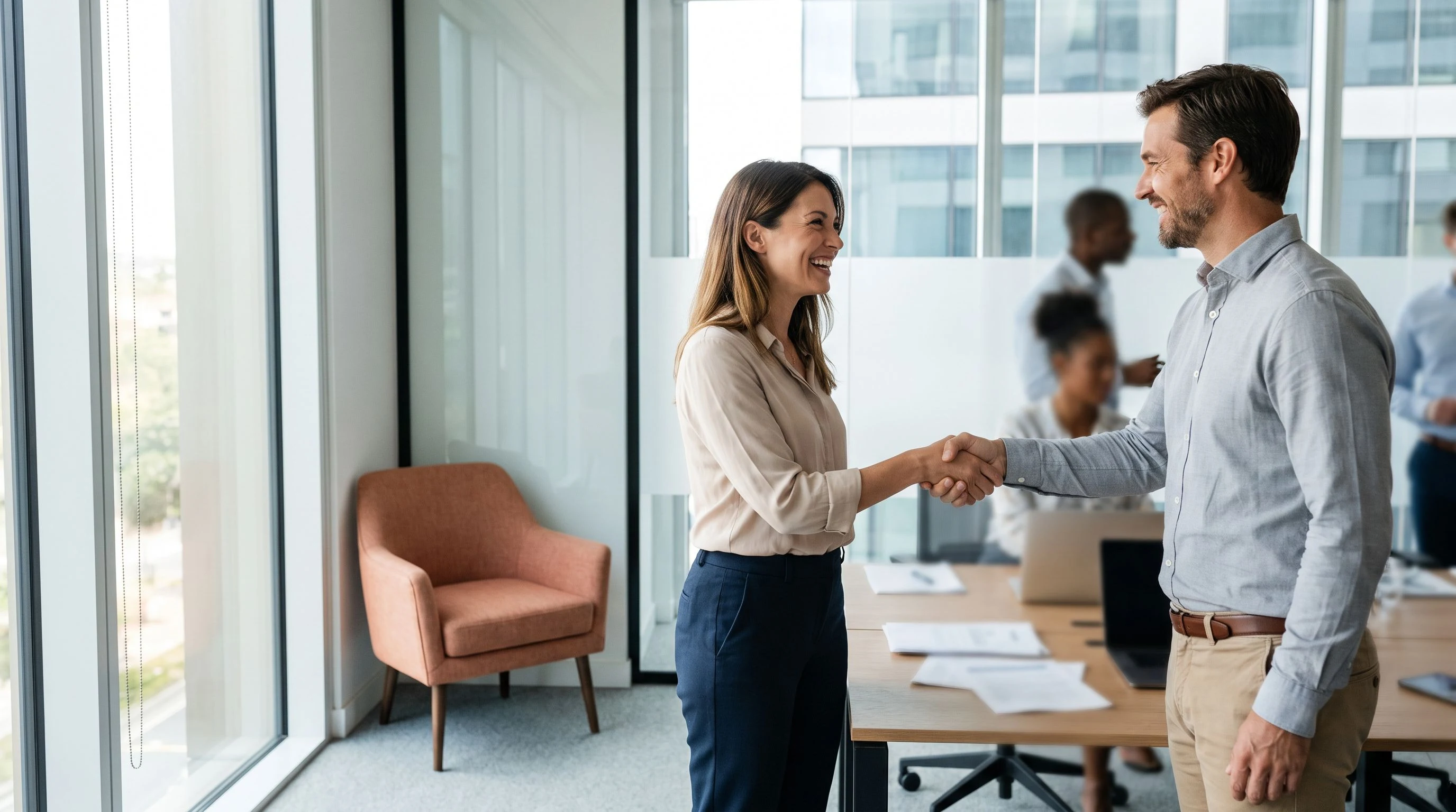 Two colleagues shaking hands after finalizing a job offer in an office setting