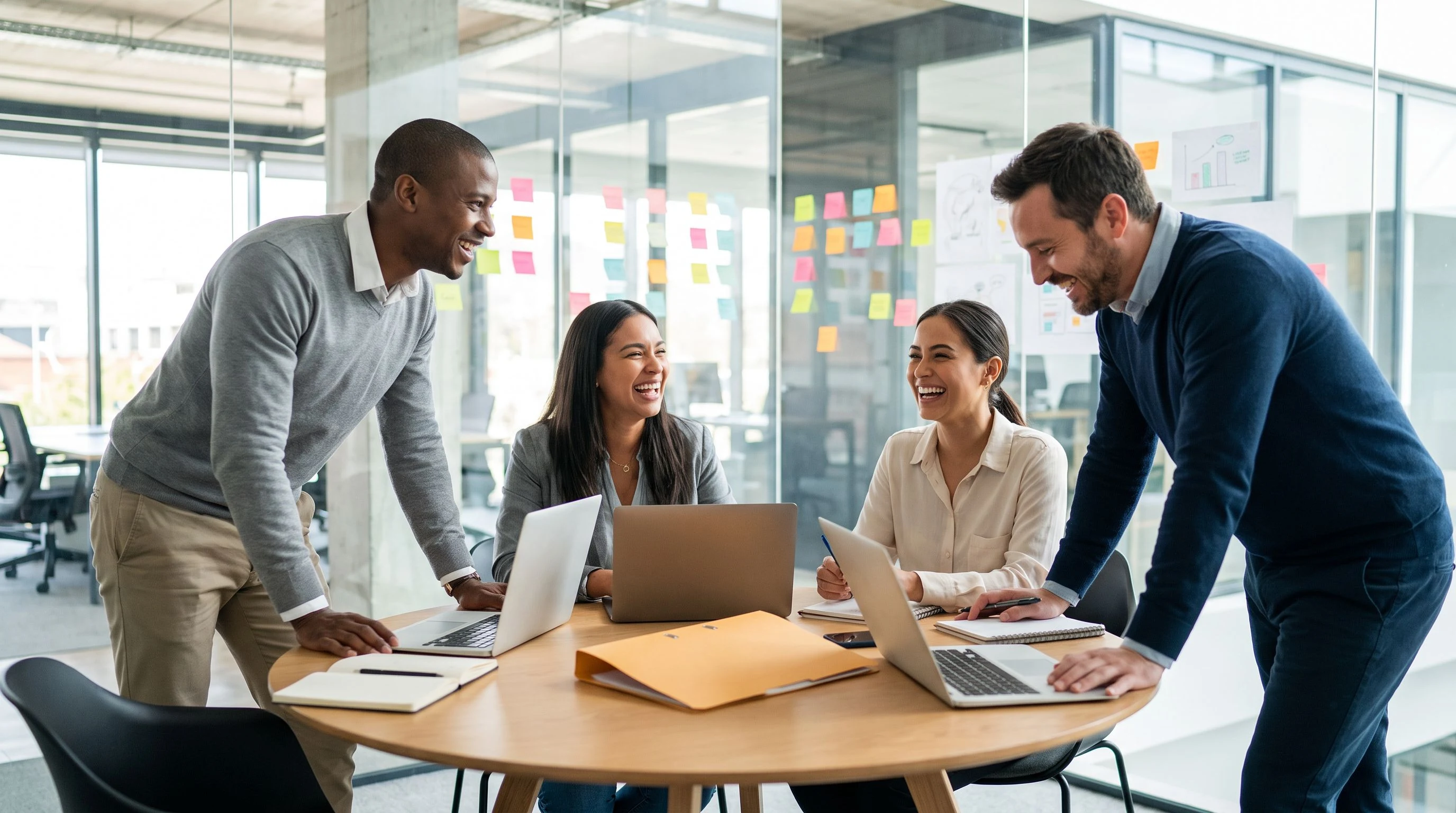 Cross-functional team of engineers and a product manager collaborating around a round conference table in a bright modern office, warm-orange folder on the table