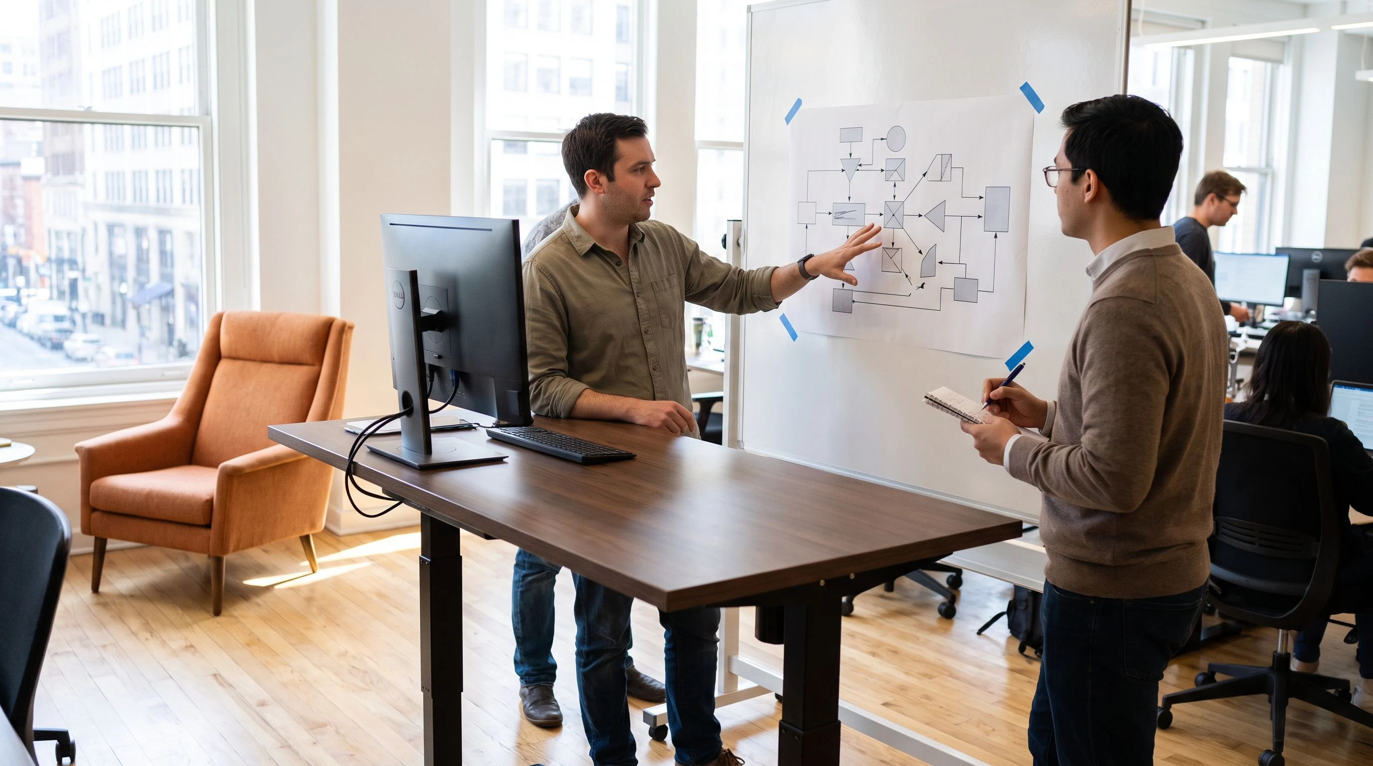 Two engineers discussing an AI agent workflow diagram on a whiteboard in a modern office
