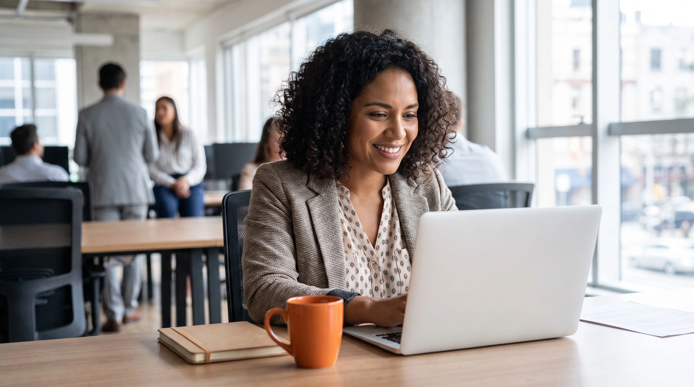 Nearshore machine learning engineer working at a laptop in a bright Costa Rica office, orange accent coffee mug on desk