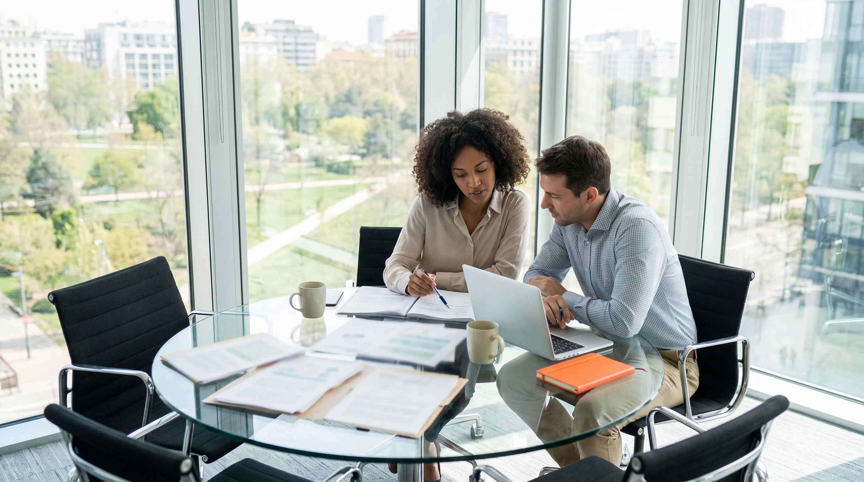 Two HR professionals reviewing recruitment pipeline documents at a modern office conference table