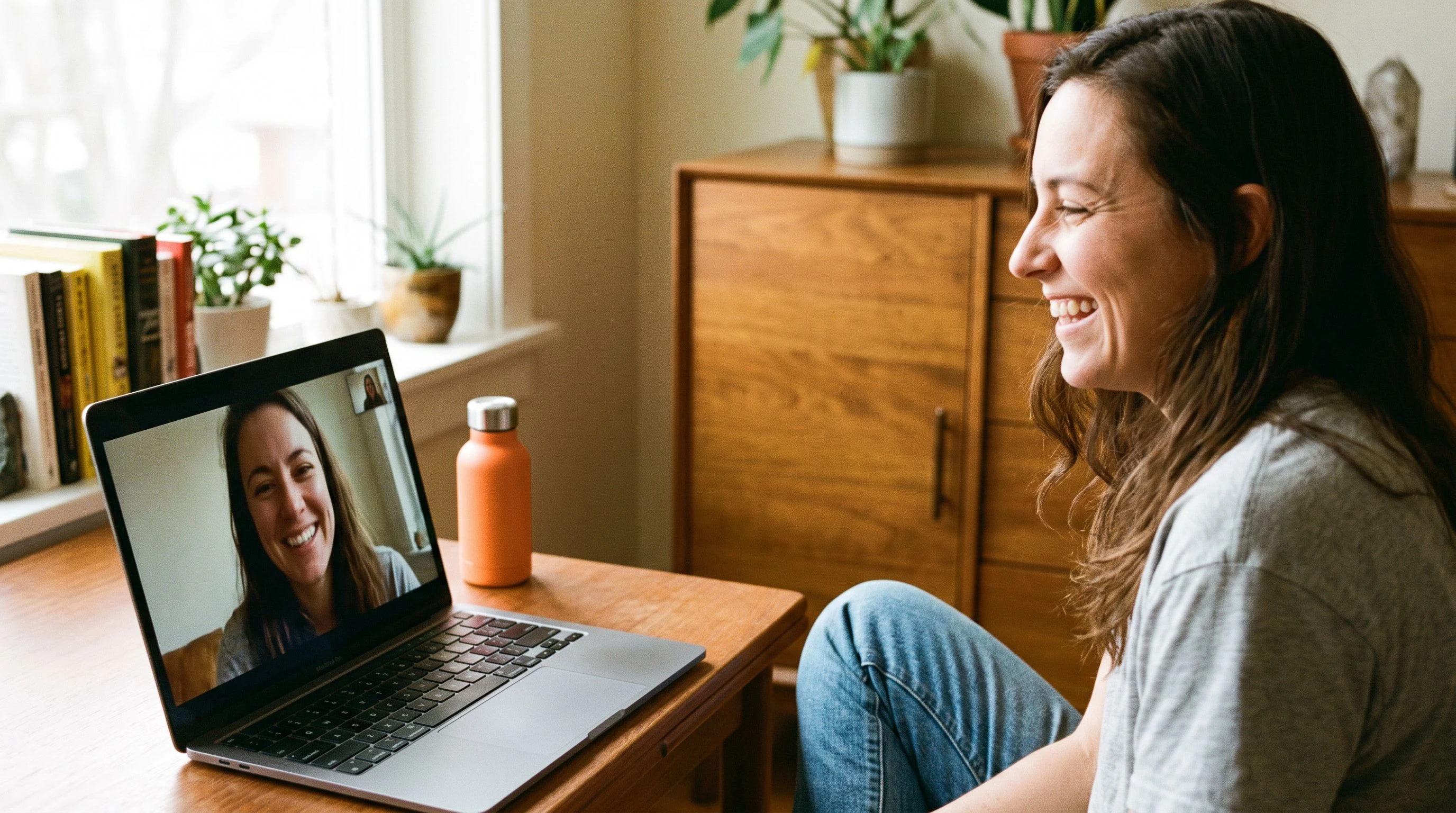 Payroll candidate on a video call interview, smiling and engaged, warm home office setting with orange water bottle