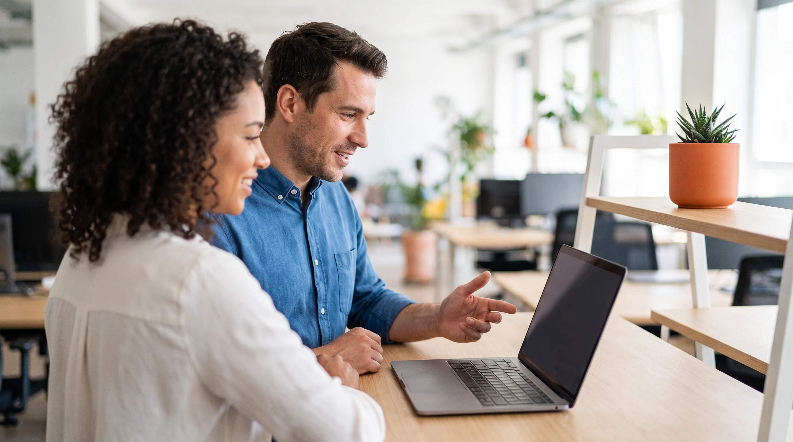 Two colleagues reviewing offshore staffing options together on a laptop