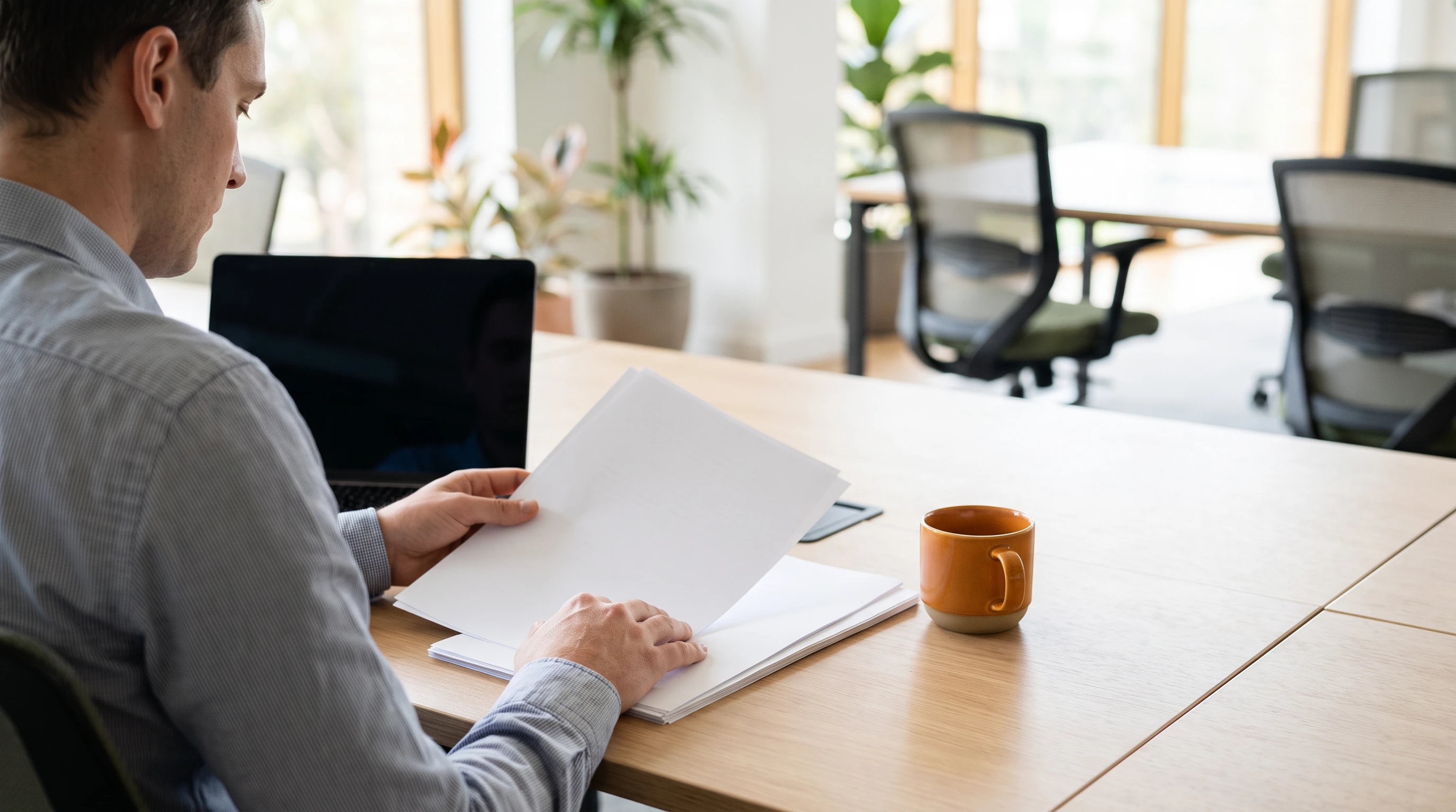 Operations manager reviewing printed data entry reports at a desk with a laptop
