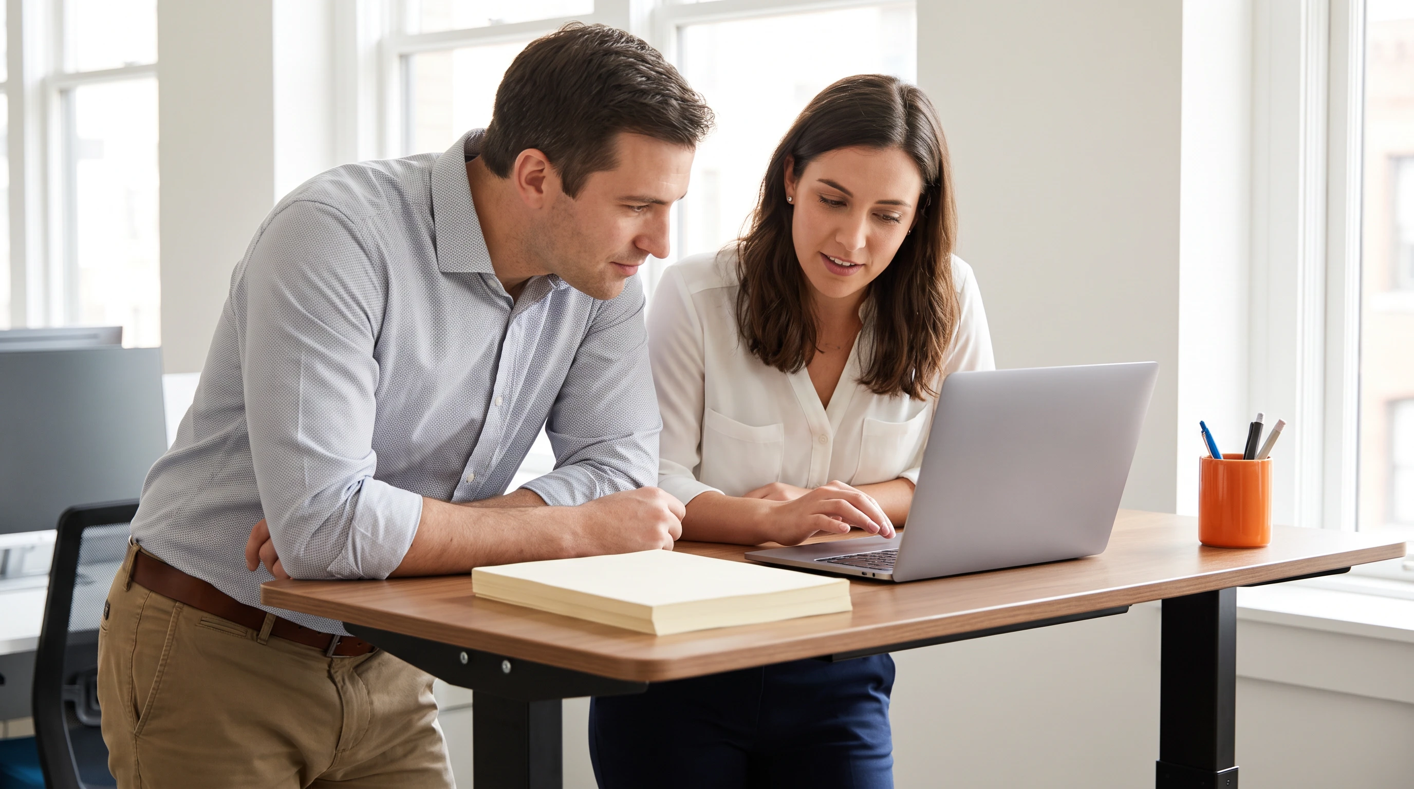 Two colleagues reviewing data entry workflow documents together at a standing desk