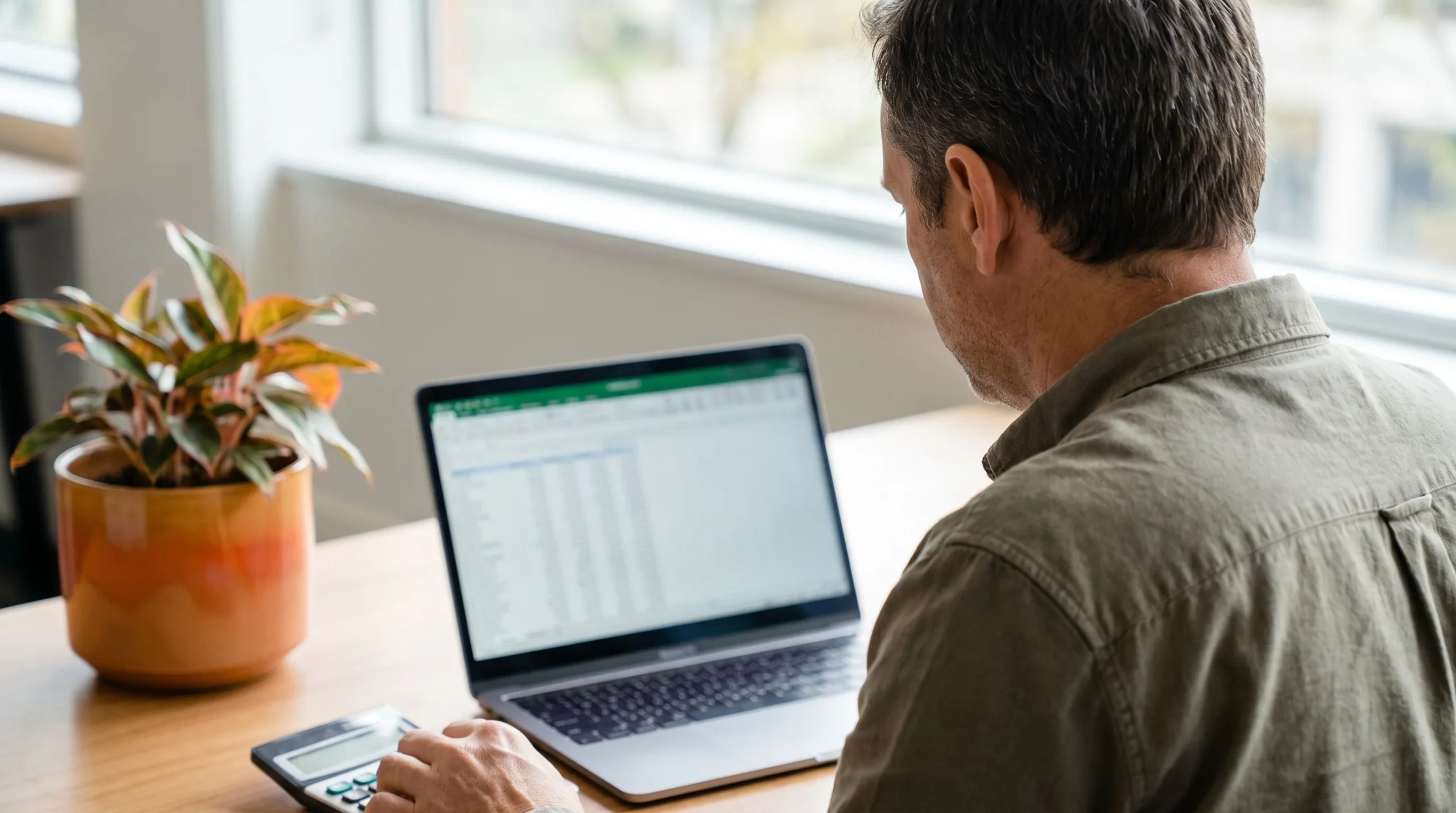 IT manager planning an outstaffing budget using a spreadsheet and calculator