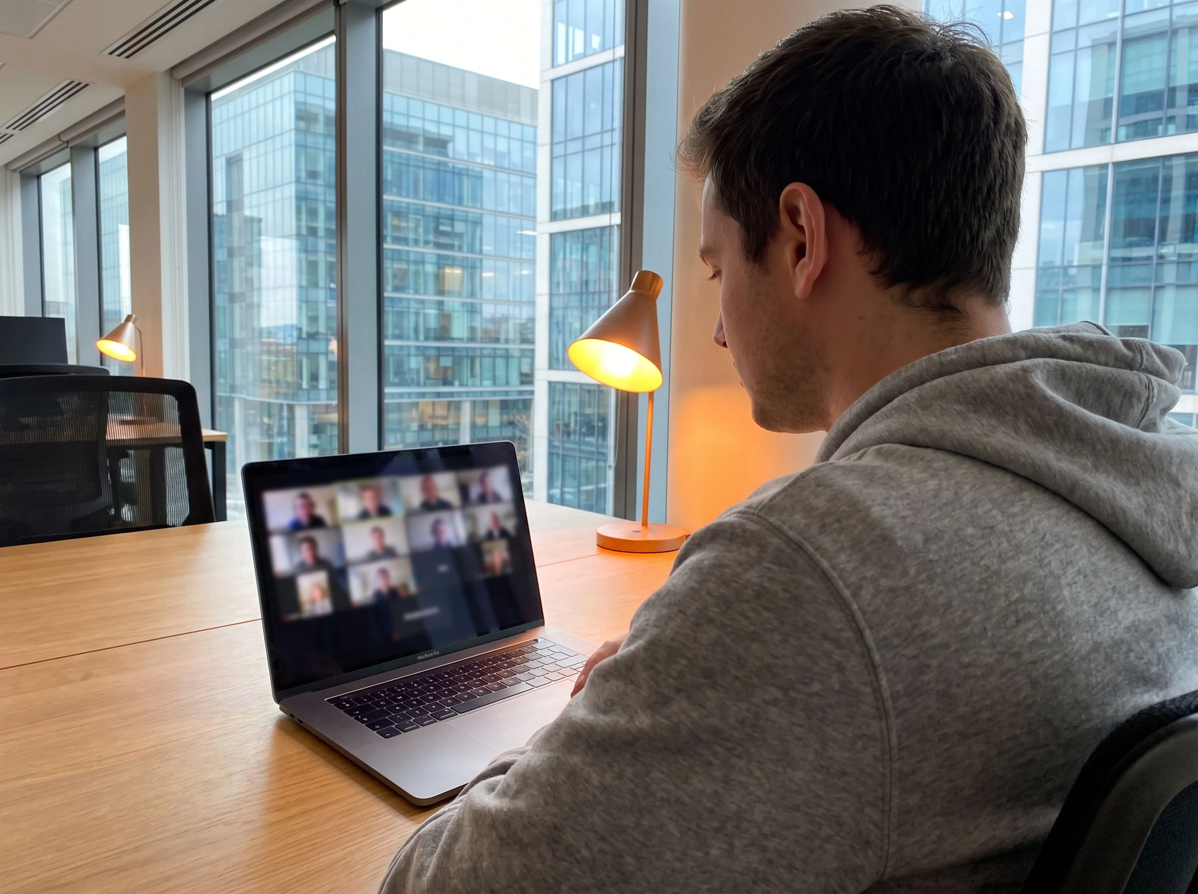 IT outstaffing developer working alongside an in-house team over video call, warm orange desk lamp accent