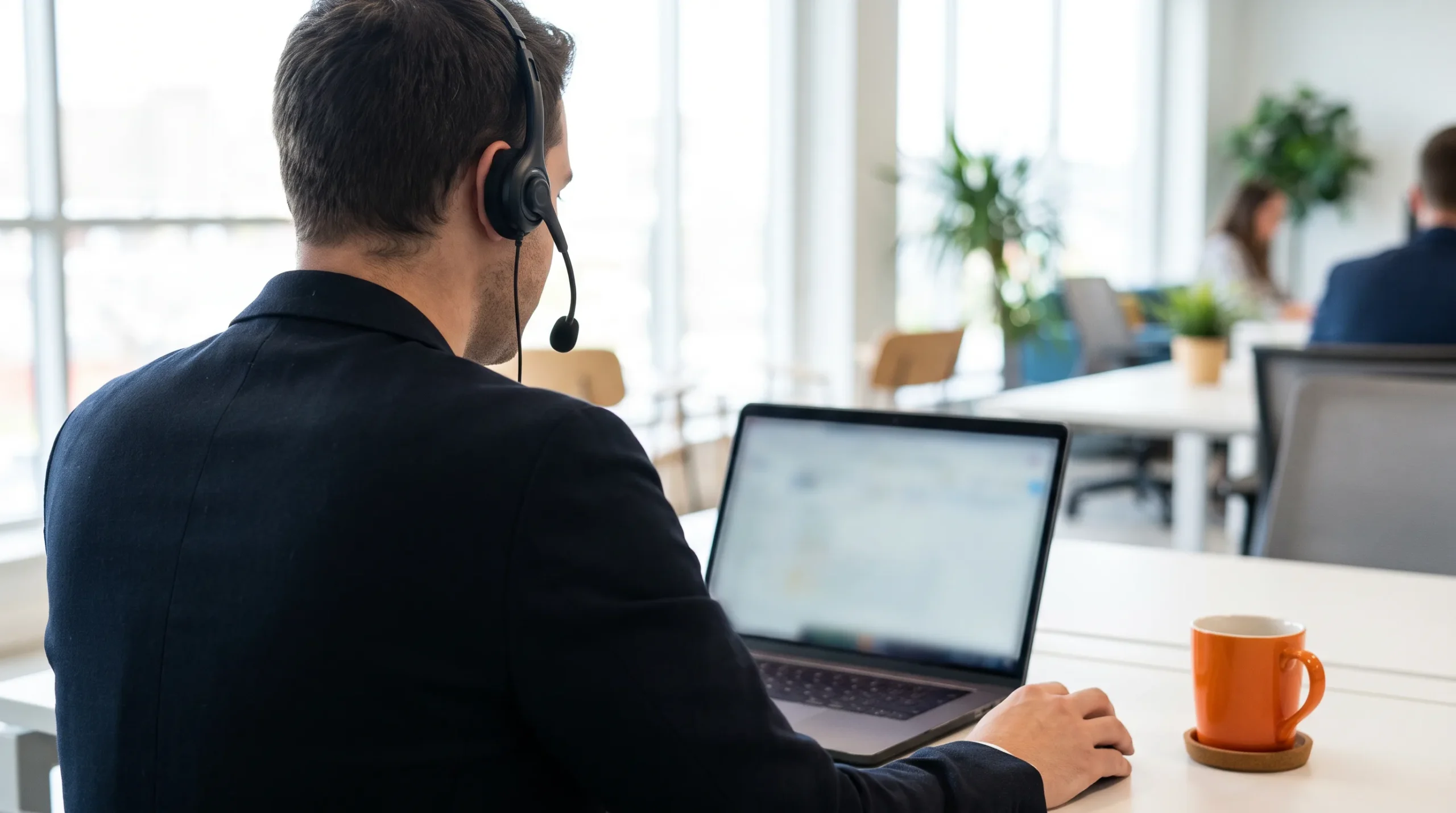 Sales development representative on headset reviewing pipeline on a laptop