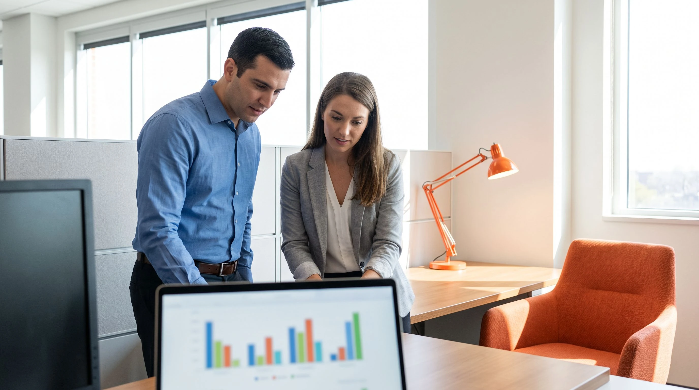 Sales manager and finance colleague reviewing an SDR budget comparison on a laptop