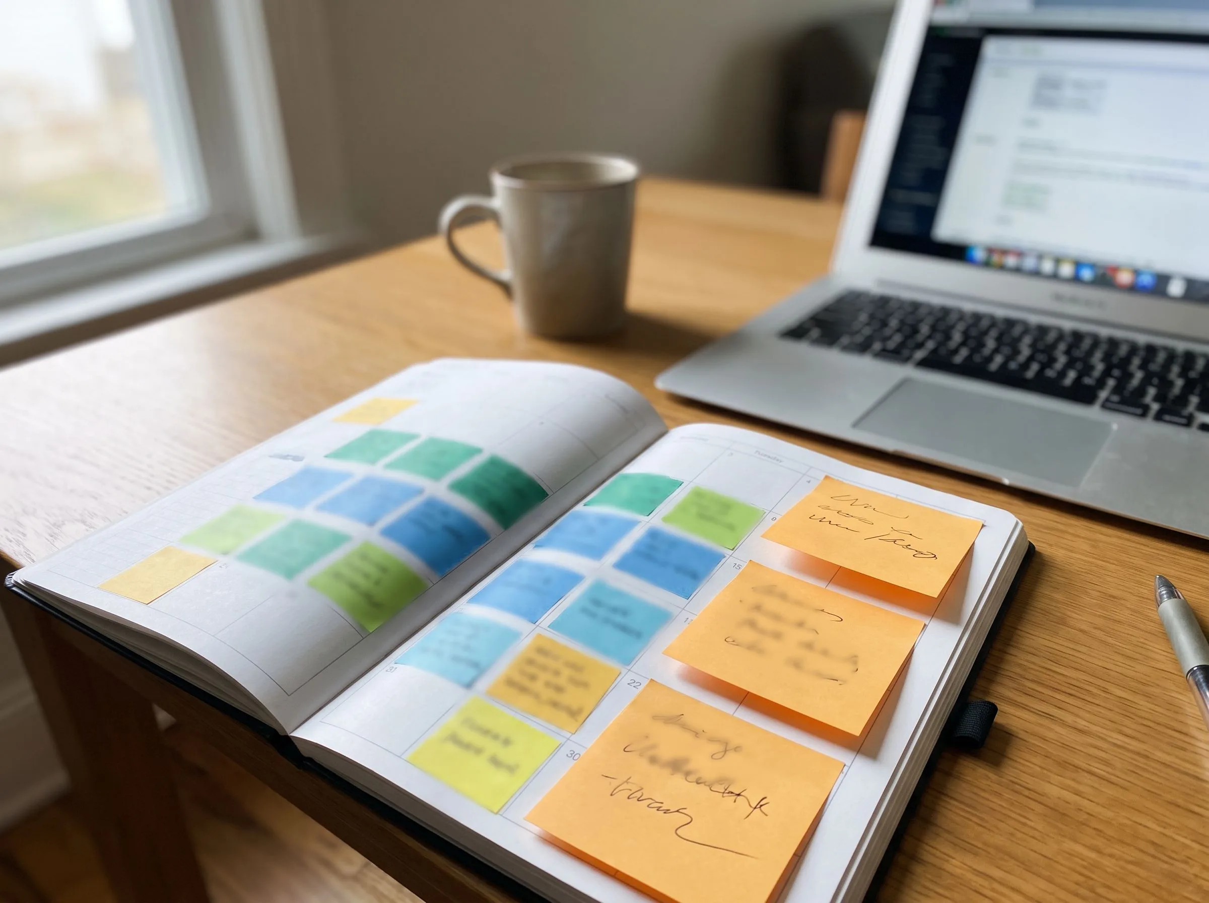 Social media content calendar spread across a desk with a warm orange sticky note accent